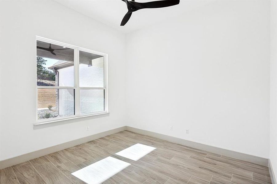 Empty room with ceiling fan and light hardwood / wood-style flooring