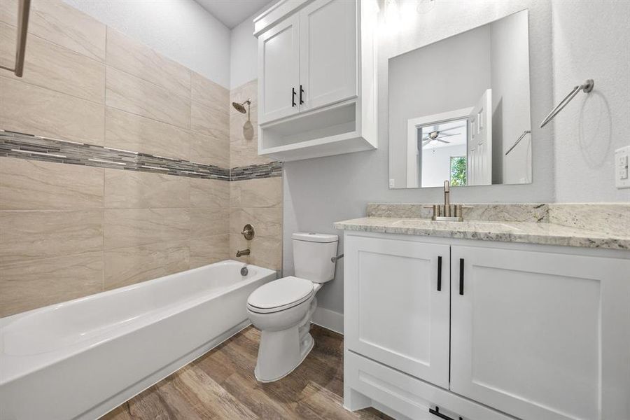 Bathroom featuring vanity, light wood-style floors, tub / shower combination, and ceiling fan