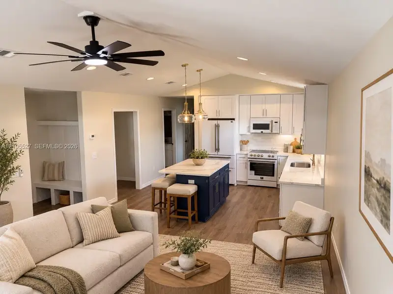 Integrated kitchen and living area featuring a vaulted ceiling and wood-finish flooring Integrated kitchen and living area featuring a vaulted ceiling and wood-finish flooring