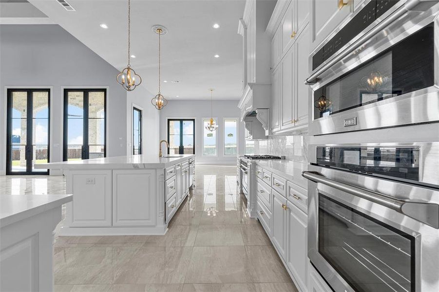 Kitchen with stainless steel appliances, a chandelier, white cabinetry, hanging light fixtures, and recessed lighting Kitchen with stainless steel appliances, a chandelier, white cabinetry, hanging light fixtures, and recessed lighting