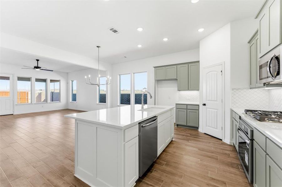 Kitchen with a ceiling fan, wood finish floors, open floor plan, decorative backsplash, and decorative light fixtures