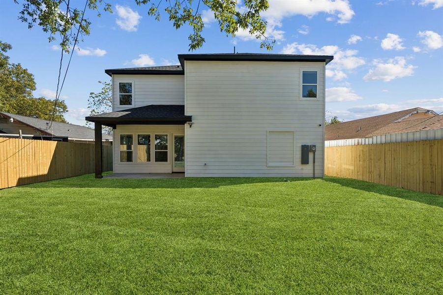 Rear view of property with a fenced backyard and a patio
