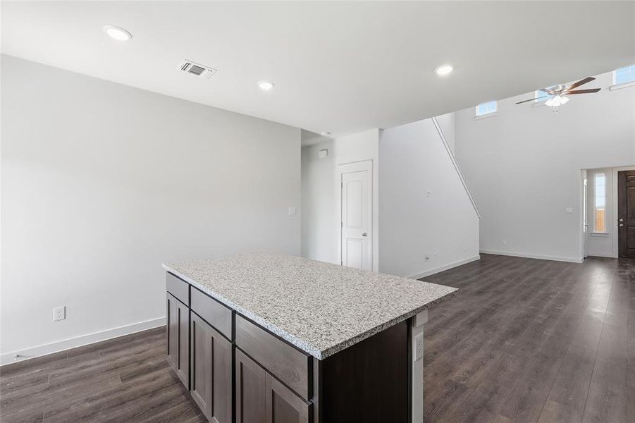 Kitchen island featuring a speckled countertop and dark wood-finish cabinetry