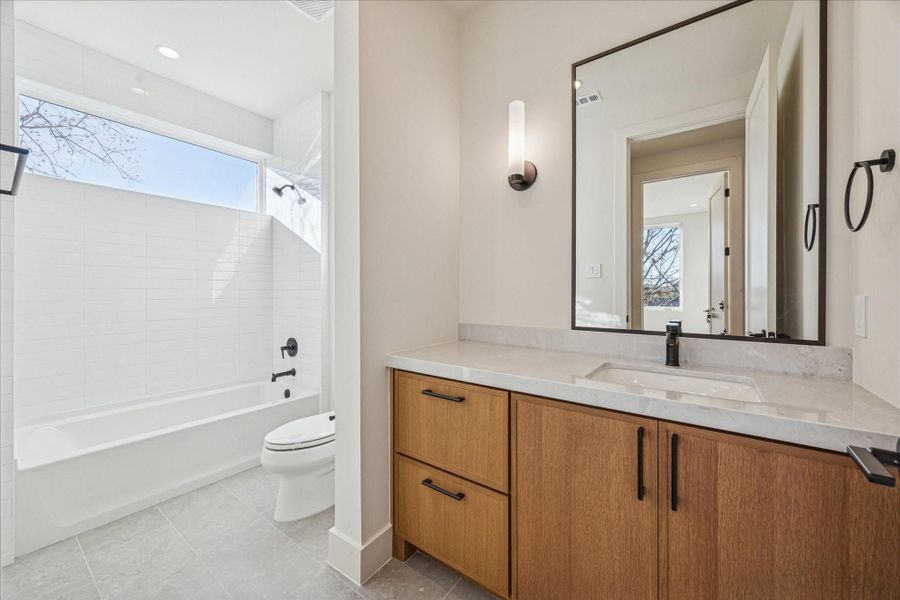 Full bathroom with a shower/tub combo, ample storage and polished dolomite countertop.