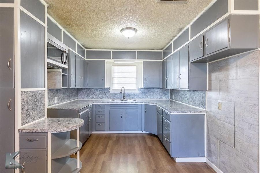Kitchen with open shelves, a textured ceiling, dark wood-type flooring, appliances with stainless steel finishes, and decorative backsplash