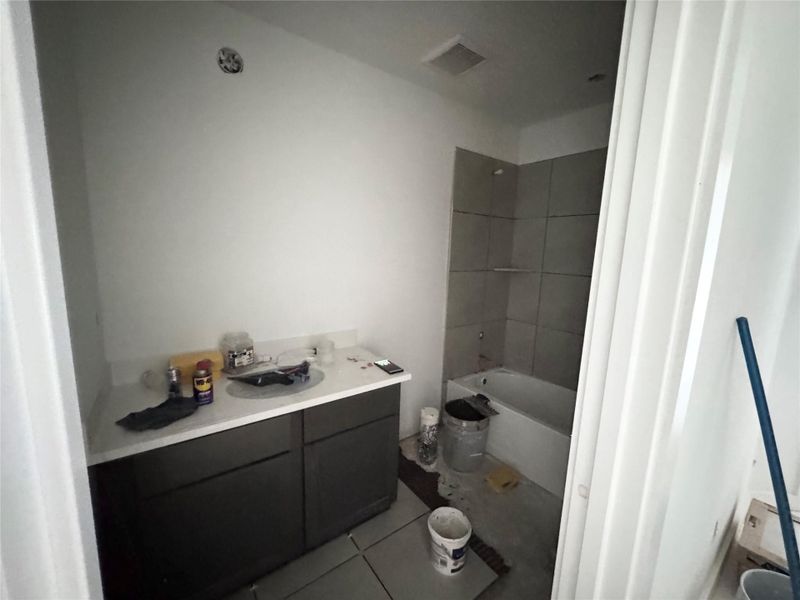 Bathroom with light tile patterned floors, vanity, and tub / shower combination