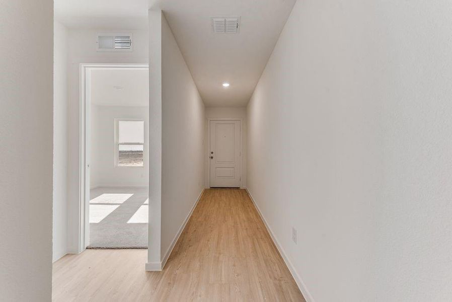 Hall with baseboards, visible vents, and light wood-style floors