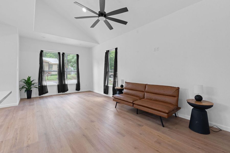 Living area with wood finished floors, ceiling fan, and high vaulted ceiling