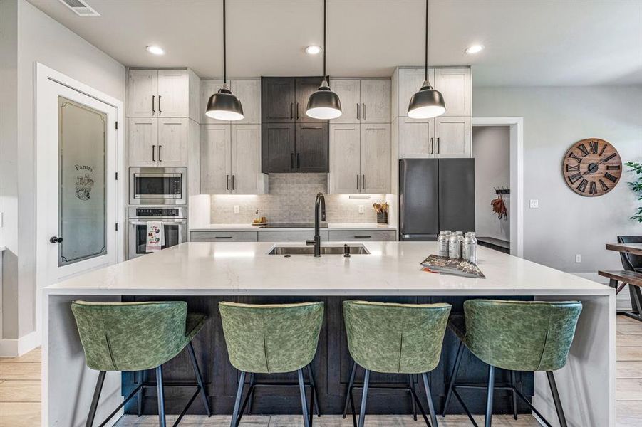 Kitchen featuring light wood-style flooring, light stone counters, tasteful backsplash, stainless steel appliances, and recessed lighting