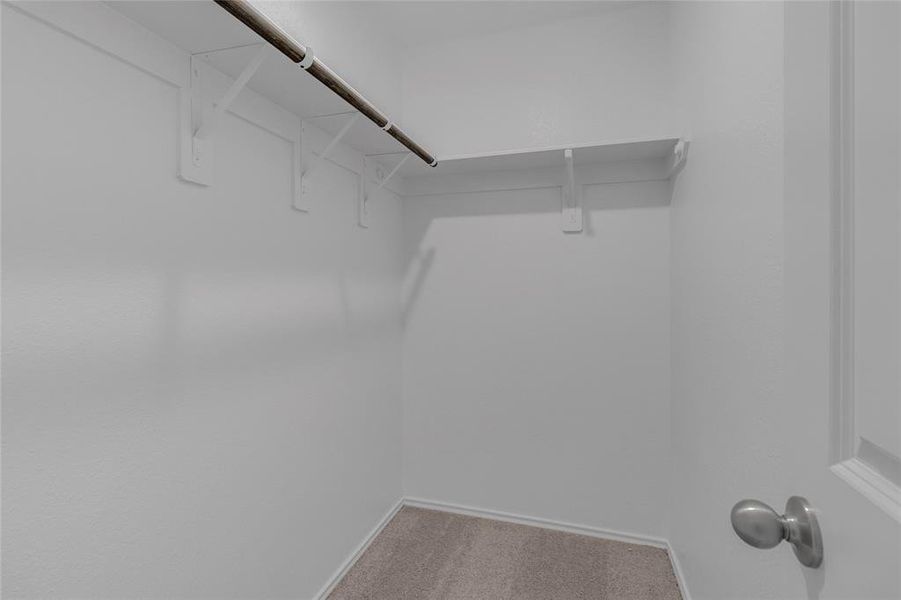 This is a huge 3rd bedroom compact walk-in closet with built-in shelves and a hanging rod, offering ample storage space in a neutral color scheme.