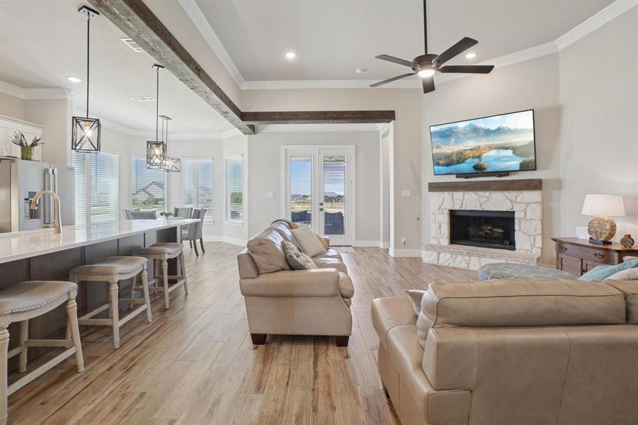 Living area with light wood finished floors, ornamental molding, recessed lighting, a fireplace, and a ceiling fan