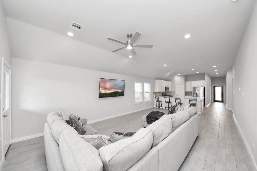 Bright and airy living room with high ceilings, recessed lighting, and a modern ceiling fan, offering a spacious layout ideal for relaxing or entertaining.