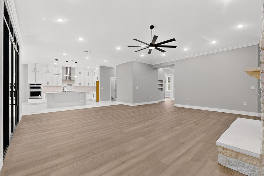 Living room featuring wood flooring, recessed lighting, a fireplace, crown molding, and a ceiling fan Living room featuring wood flooring, recessed lighting, a fireplace, crown molding, and a ceiling fan