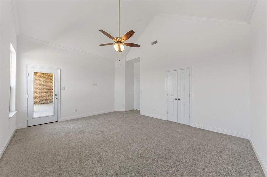 Empty room with ceiling fan, light carpet, high vaulted ceiling, baseboards, and ornamental molding