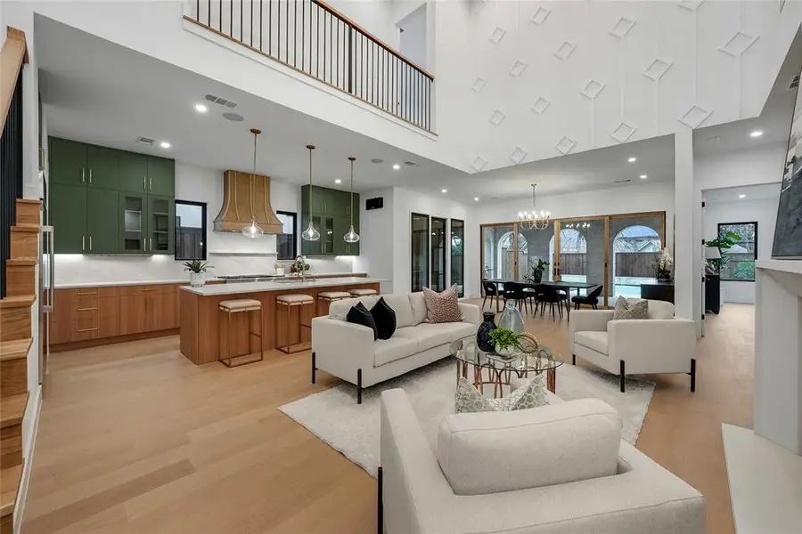 Living room featuring light wood-style floors, hanging lights, and a high ceiling Living room featuring light wood-style floors, hanging lights, and a high ceiling