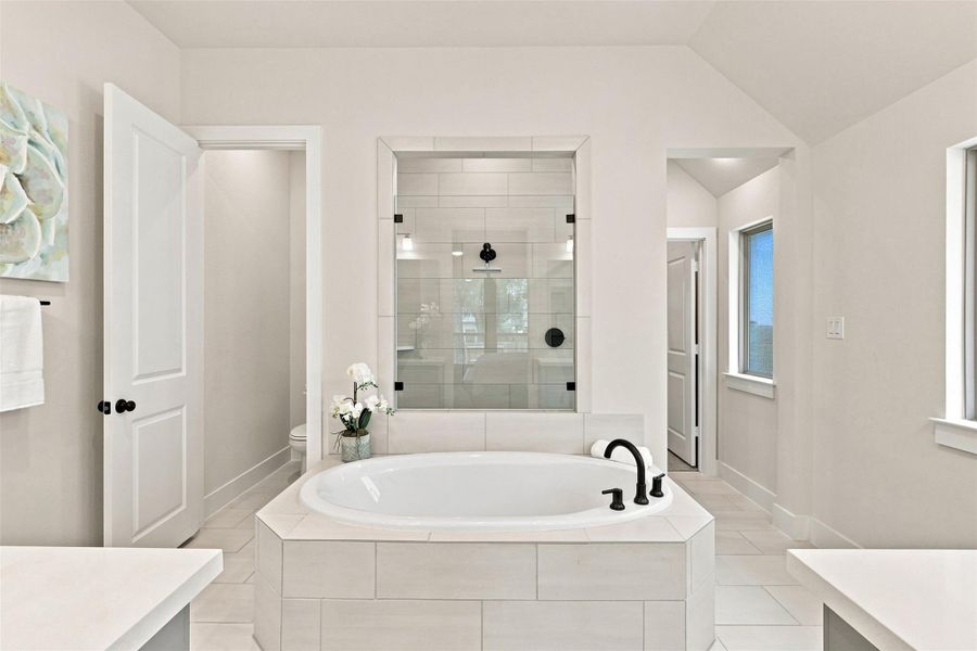 Indulge in a tranquil retreat featuring a spacious soaking tub and an adjacent glass-enclosed shower.