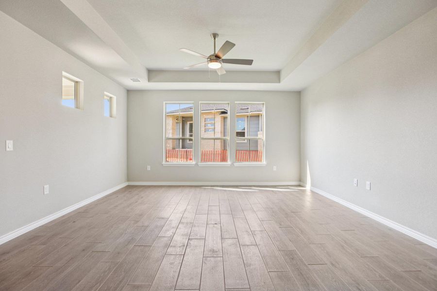 Spare room featuring light wood finished floors, a raised ceiling, and ceiling fan