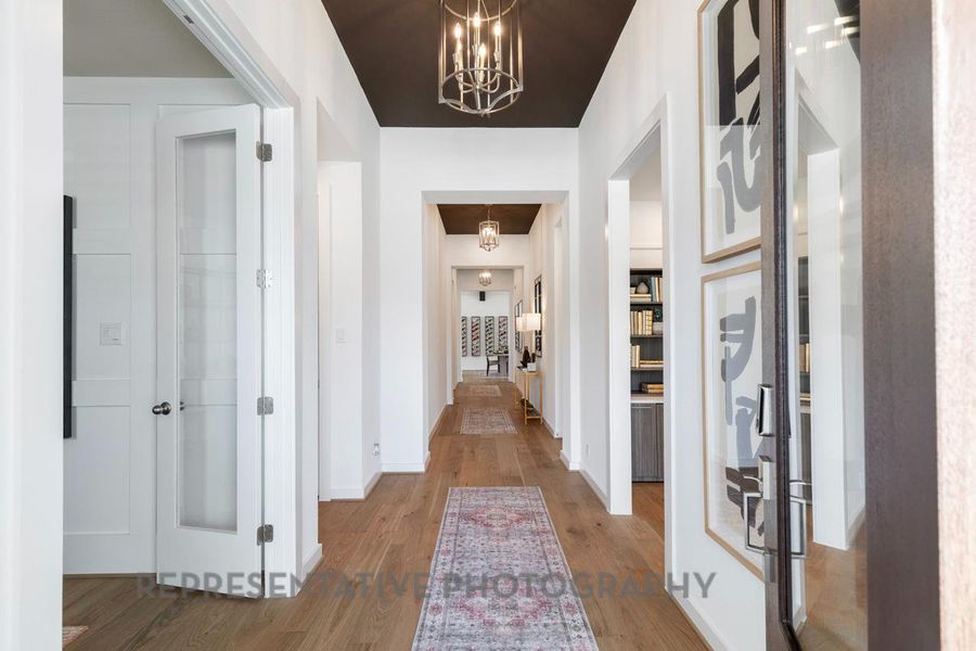 Hall with wood finished floors and a chandelier
