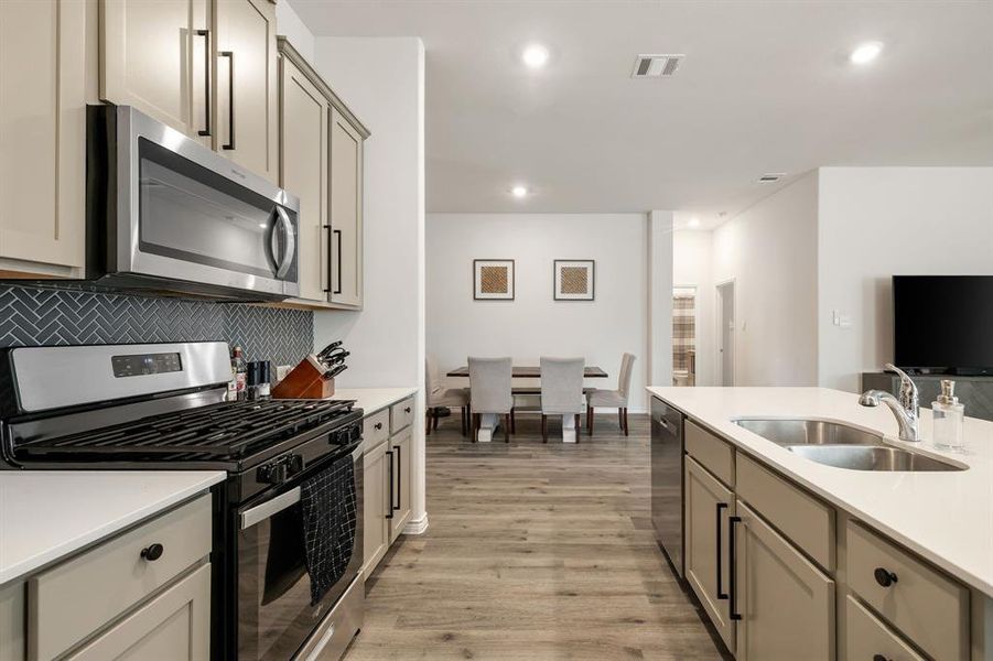 Kitchen featuring stainless steel appliances, gray cabinetry, light wood-style flooring, recessed lighting, and tasteful backsplash Kitchen featuring stainless steel appliances, gray cabinetry, light wood-style flooring, recessed lighting, and tasteful backsplash