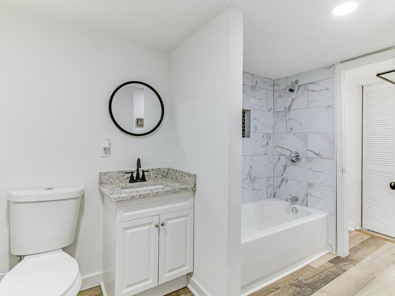 Full bath with vanity, wood finished floors, and shower combination Full bath with vanity, wood finished floors, and shower combination