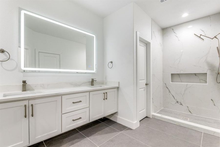 Bathroom with tile patterned flooring, vanity, and a tile shower