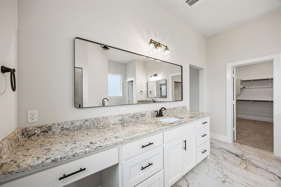 Bathroom with a walk in closet, light marble finish flooring, and vanity Bathroom with a walk in closet, light marble finish flooring, and vanity