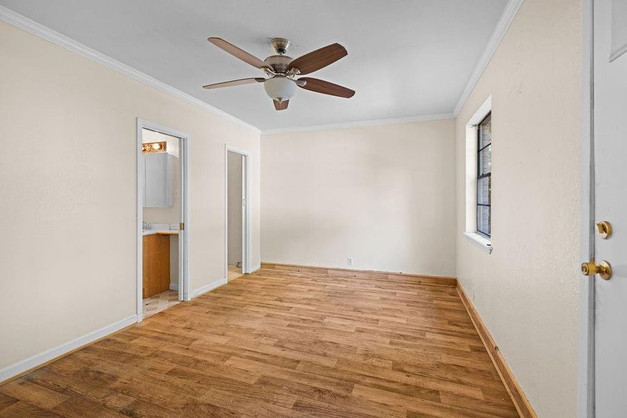 Primary bedroom featuring crown molding, light wood-type flooring, ceiling fan, and connected bathroom