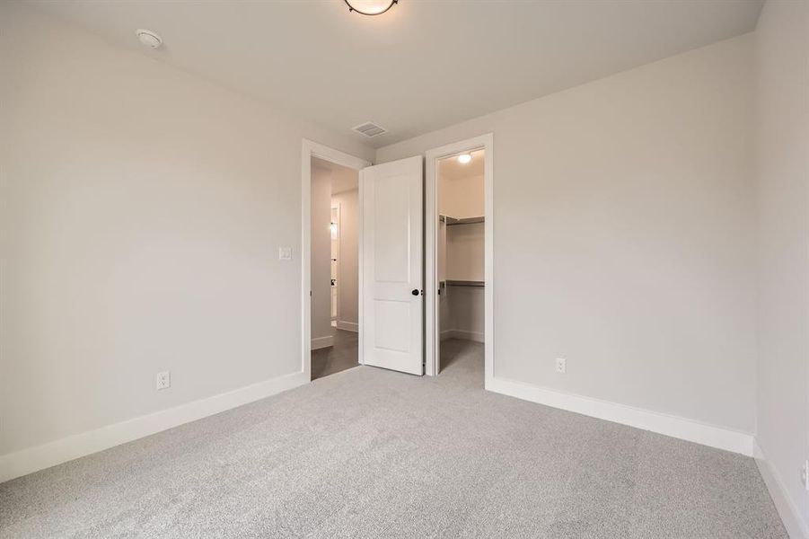 Unfurnished bedroom featuring a closet, carpet flooring, visible vents, baseboards, and a spacious closet Unfurnished bedroom featuring a closet, carpet flooring, visible vents, baseboards, and a spacious closet