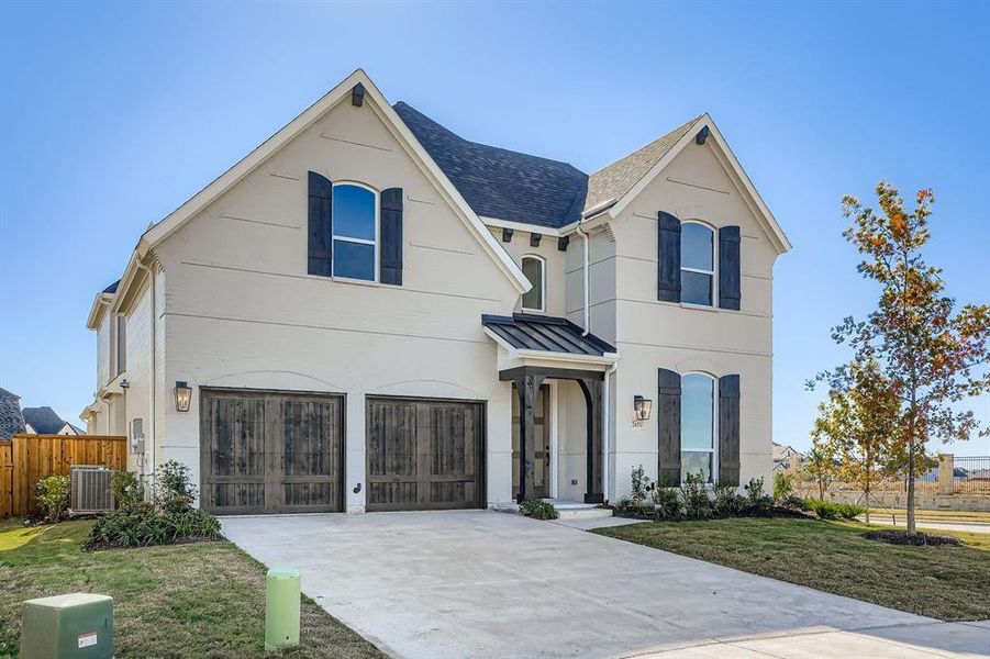 View of front facade with a standing seam roof, a garage, driveway, a metal roof, and stucco siding