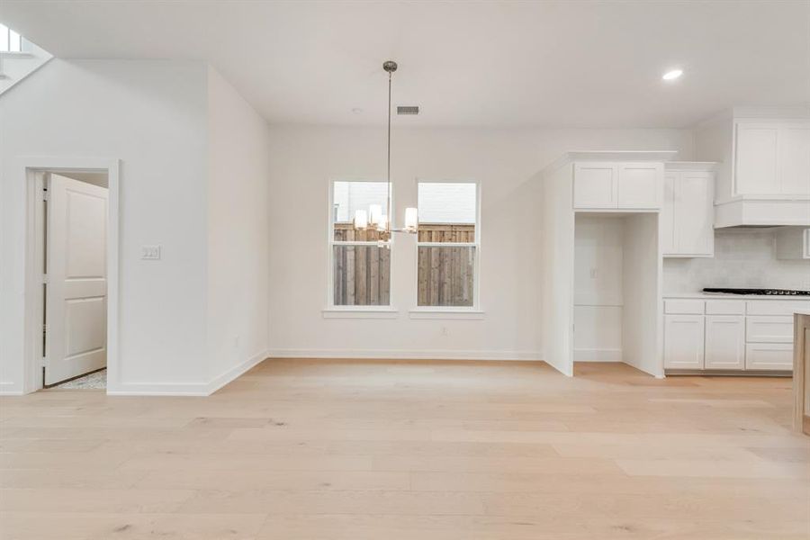 Unfurnished dining area featuring light wood-type flooring, a chandelier, and recessed lighting Unfurnished dining area featuring light wood-type flooring, a chandelier, and recessed lighting
