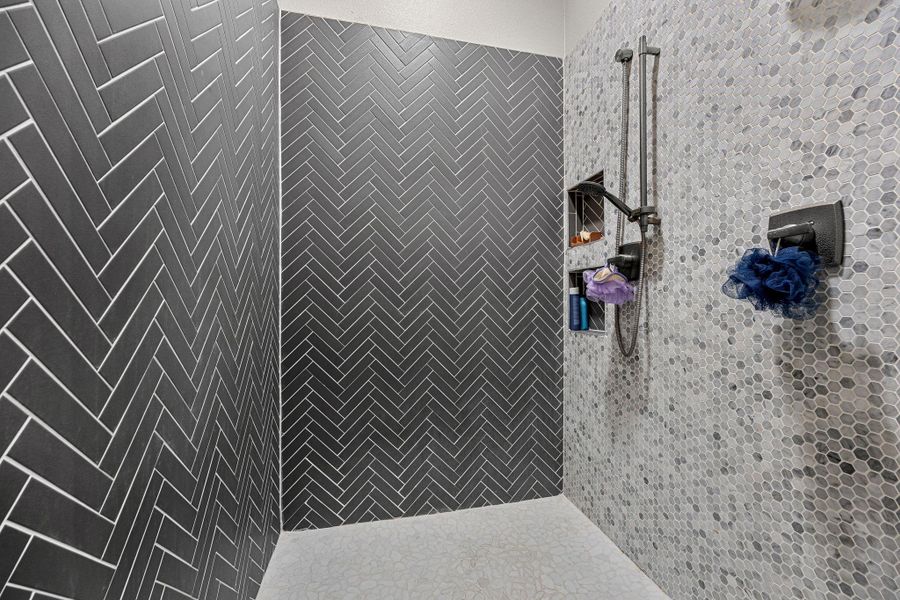Elegant shower featuring contrasting herringbone and mosaic tile patterns for a contemporary bathing experience. Elegant shower featuring contrasting herringbone and mosaic tile patterns for a contemporary bathing experience.