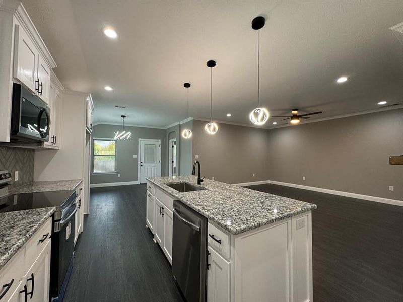 Kitchen with stainless steel appliances, ceiling fan, a kitchen island with sink, sink, and white cabinetry