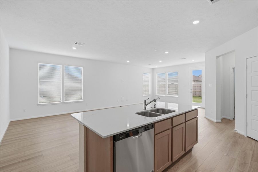 The central kitchen island features a durable quartz countertop, an undermount stainless steel sink, with a Moen Pull-Out Spout faucet. The kitchen island has additional storage space, increased counter and prep space, and is the social hub of the home--where family and guests gather and interact on the added breakfast bar!