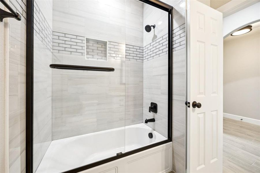 Bathroom with combined bath / shower with glass door and wood finished floors Bathroom with combined bath / shower with glass door and wood finished floors