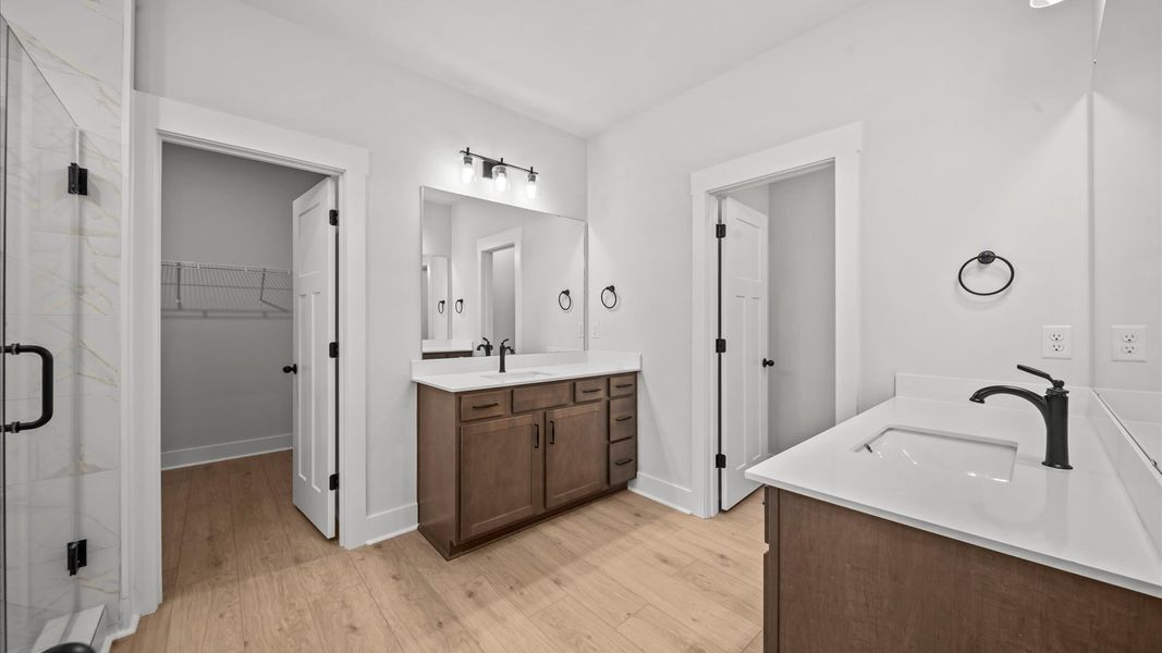 Superior en-suite primary bathroom with stylish separate vanities and tiled walk-in shower