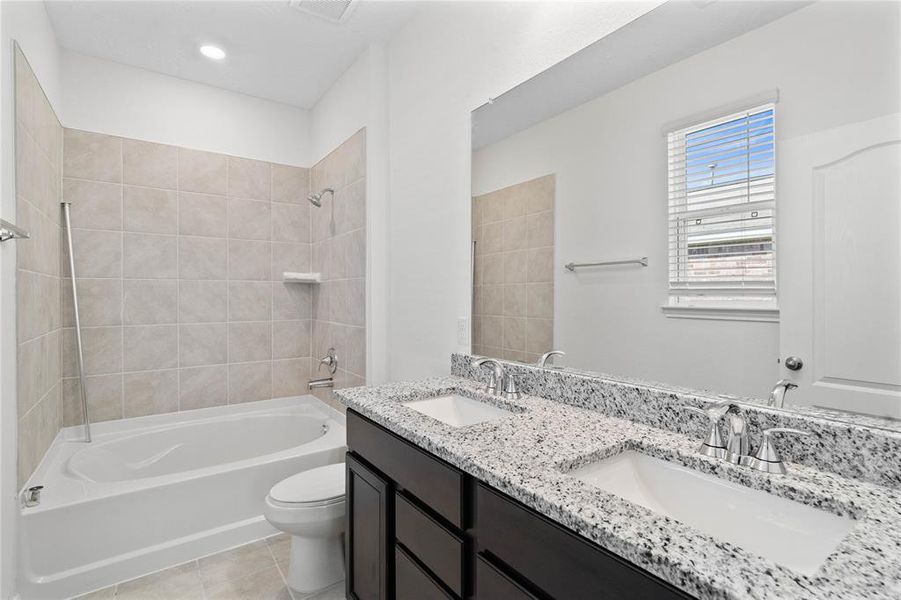 This primary bathroom is definitely move-in ready! Featuring a tub/shower combo with tile surround, stained cabinets with granite countertops, spacious walk-in closet with shelving, high ceilings, custom paint, sleek and modern finishes.