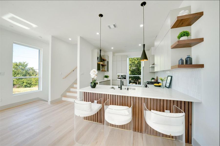 Kitchen with kitchen peninsula, extractor fan, white cabinetry, pendant lighting, and sink