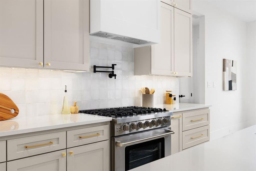 Kitchen featuring custom range hood, high end stove, and backsplash