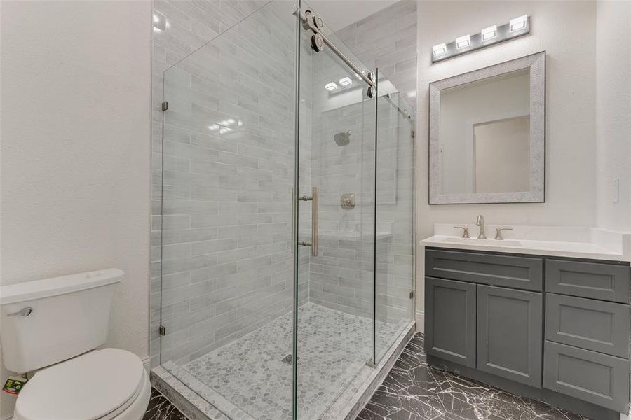 Modern bathroom featuring a glass-enclosed shower with subway tile surround and pebble tile flooring Modern bathroom featuring a glass-enclosed shower with subway tile surround and pebble tile flooring