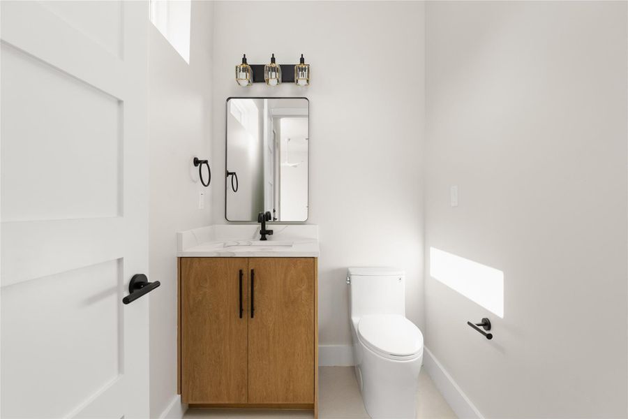 Minimalist design elements define this crisp powder room with a natural wood vanity.