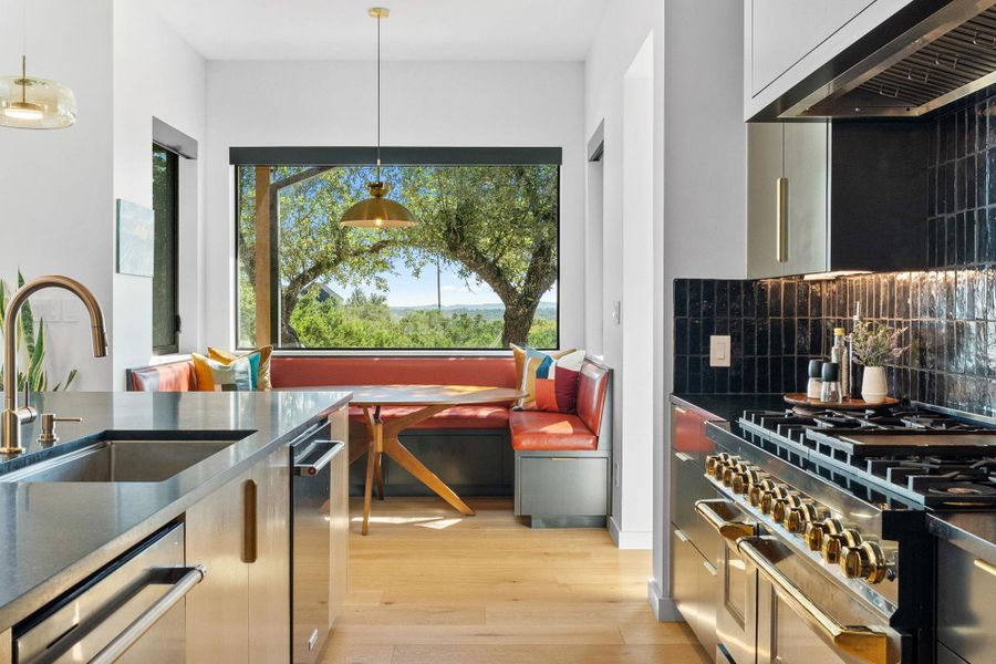 Modern kitchen featuring a stainless steel gas range, black subway tile backsplash, and light wood-finish flooring