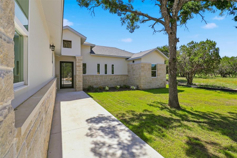 Modern exterior featuring a prominent stone facade, stucco finishes, and a contemporary glass-paneled entry door Modern exterior featuring a prominent stone facade, stucco finishes, and a contemporary glass-paneled entry door