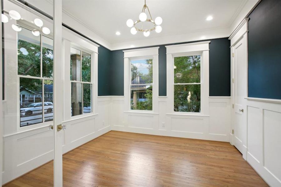 The study is dressed with panel molding and a fun globe light fixture. A sizeable closet is off the door to the right.