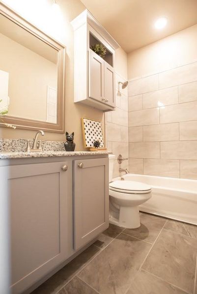 Bathroom with toilet, shower / bathing tub combination, tile patterned flooring, and vanity