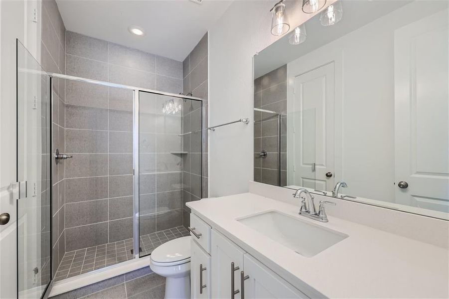 Bathroom featuring tile flooring, an enclosed shower, toilet, and vanity