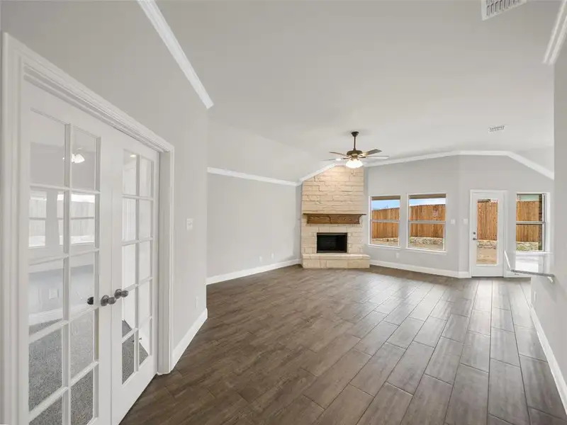 Unfurnished living room with ceiling fan, visible vents, dark wood-style flooring, lofted ceiling, and baseboards Unfurnished living room with ceiling fan, visible vents, dark wood-style flooring, lofted ceiling, and baseboards