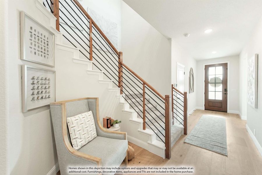 Bright entryway with wood and metal staircase railing, light hardwood floors, and glass-panel front door Bright entryway with wood and metal staircase railing, light hardwood floors, and glass-panel front door