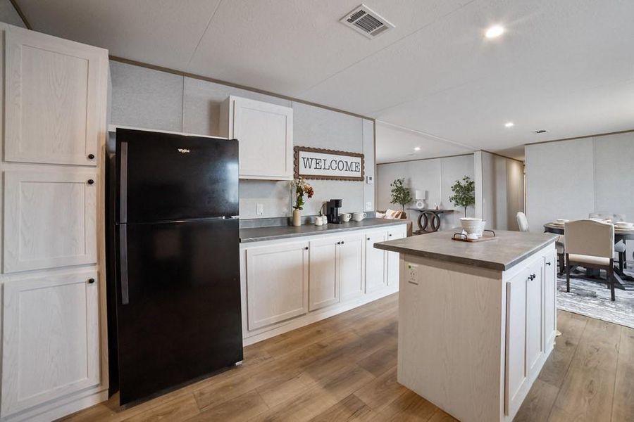 Kitchen with refrigerator, a center island, white cabinetry, and recessed lighting Kitchen with refrigerator, a center island, white cabinetry, and recessed lighting