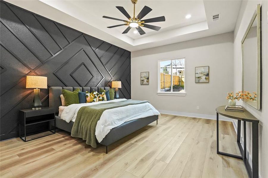 Bedroom featuring an accent wall, light wood-style floors, a ceiling fan, and a decorative wall