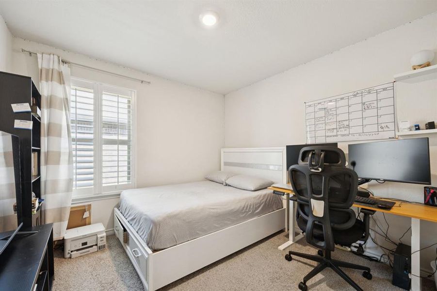 Bedroom with light colored carpet and an office area